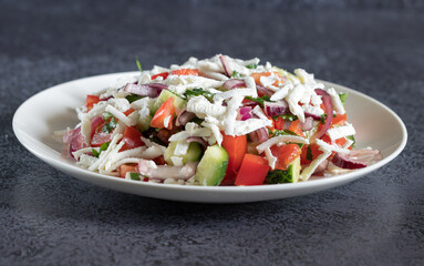 Bulgarian shopska salad with vegetables and brynza on dark background close up