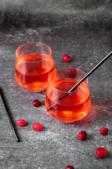 Red cranberry drink in transparent glasses with tubes on a gray background