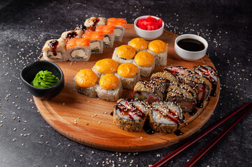 Japanese sushi and rolls, on a wooden board, with sauce, wasabi and ginger