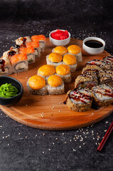 Japanese sushi and rolls, on a wooden board, with sauce, wasabi and ginger
