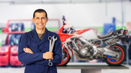 Front view portrait of a motorcycle mechanic posing standing looking at you in a mechanical...