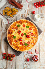Pie with smoked sausages and cheese on a wooden background