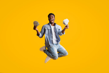 Emotional black guy in denim celebrating success, holding cash