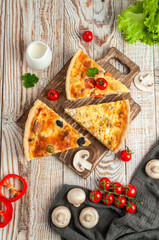 Pies in pieces on a wooden board, on a light wooden background with greens, cherries, mushrooms