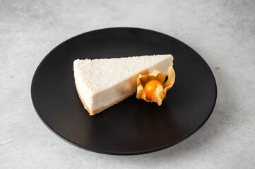 Cheesecake on a dark dish on a gray background in a minimalist style