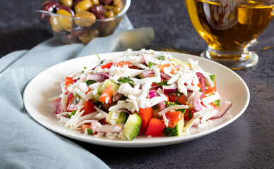 Shopska salad with vegetables and brynza on dark background with gray textiles