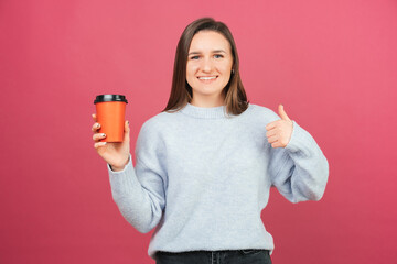 Cheerful woman is showing like gesture while holding a takeaway cup.