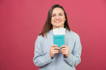 Naklejka premium Content young smiling woman holding passport with some flight tickets.
