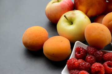 Sweet corn, apples, apricots and other berries and fruits on dark stone table