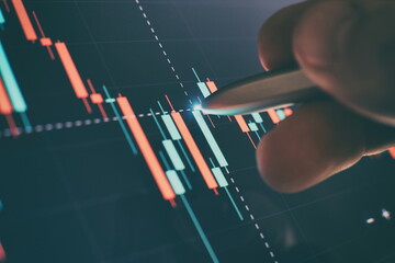 Financial chart with pen, stock analysis data for business background on digital screen. Graphs of...