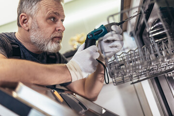 Man with toolbox repairing dishwasher in a household.