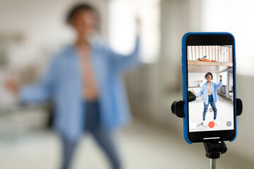 Cheerful black woman filming video on cell phone