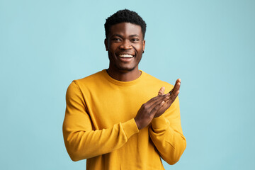 Emotional black guy clapping hands on blue