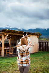 Back view of woman taking photo of mountains on mobile