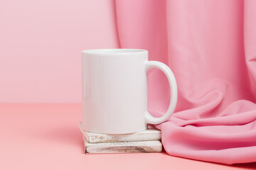 Obraz na płótnie Canvas Blank mockup mug on wooden coaster with textile drape on pink background, cup for logo, design and template