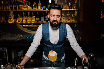 A man learns how to make cocktails at the bar. Happy bartender showing his ready cocktail.