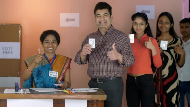 A group of happy voters and the election officer doing a thumbs-up gesture - voter id cards  new voters  an Indian citizen. A middle-aged lady officer / Chunaav Adhikaari working at her desk in a p...