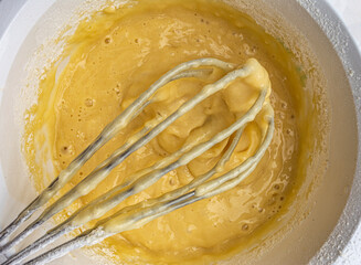cupcake batter and whisk on white background top view