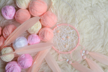 Handmade vintage dream catcher and small balls of yarn on soft white background