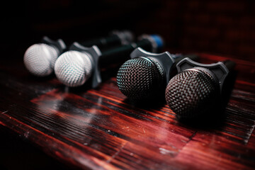 Several microphones lie on a wooden table. Karaoke is waiting for guests.