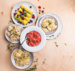 Assortment of Italian pasta dishes. Different types of tortellini, ravioli, dumpling, pierogi, crepes on wooden   background.