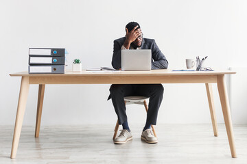 Black CEO feeling tired, working overtime, suffering from headache or stress, making error, sitting...