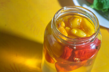 Canned yellow peppers in a jar on wooden background,natural light