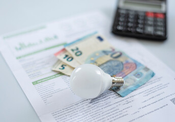 a light bulb, euro bills, and a calculator on an electric bill, . Rising cost of electricity  . Payment of electricity bills. Increasing the concept of electricity prices. - obrazy, fototapety, plakaty