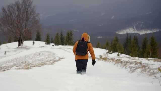 male tourist with a backpack walking in deep snow