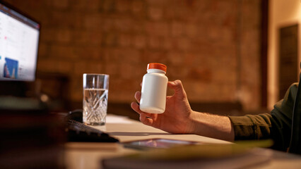 Cropped of male trader holding jar with pills