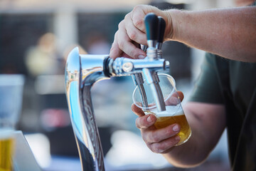 A device for pouring alcoholic beverage beer. Male hands of the bartender. A bar or cafe on the...