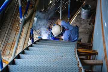 Welding male worker metal arc is part of tank stairway.