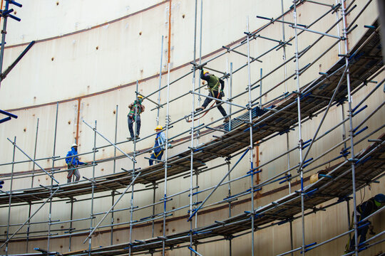 Worker male assembly in progress storage tank oil inspection scaffolding work at high