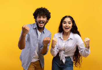 Portrait of overjoyed indian man and woman with open mouth cheering and staring at camera over...