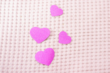 Pink hearts on a pink background. The textile background is pink.