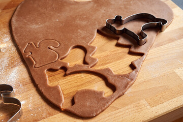 Cutting out pastry shapes for gingerbread Christmas cookies on a table