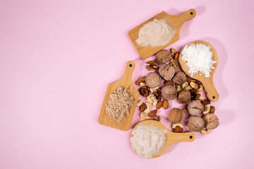 Various gluten free flour on a white table with nuts. Almonds, cashews, walnuts. Flat lay. Pink...