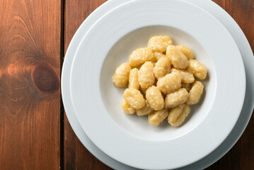 Piatto di gnocchi di patate conditi con burro e formaggio, Cucina Italiana 