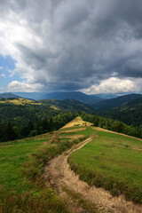 Road is high in mountains, fields, forests and farmland on background of blue sky, Carpathians, Ukraine