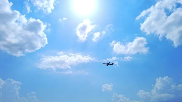 Flying airplane in the cloudy blue sky. Cloudscape sky with copy space. Airplane taking off over mountains and sea. Travel by air transport