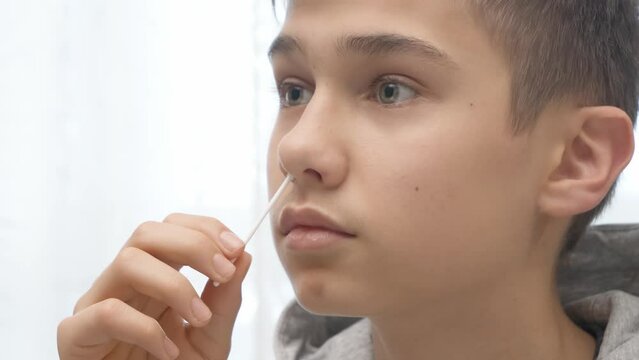 Teenage boy taking antigen self-test for Covid-19 with rapid diagnostic test kit. Kid using nasal swab while doing coronavirus test at home before go to school lessons