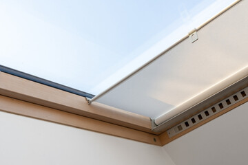 Attic or mansard window in wooden frame with roller blinds