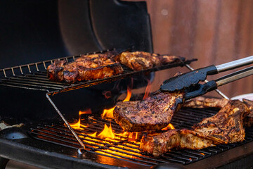 gas grill with grilled meat and grill tongs - obrazy, fototapety, plakaty