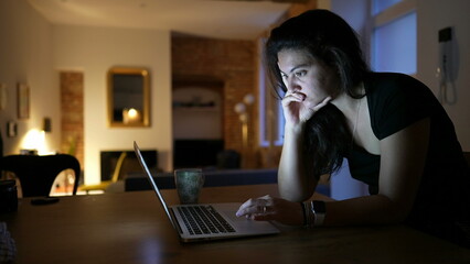 Woman looking at laptop screen at night