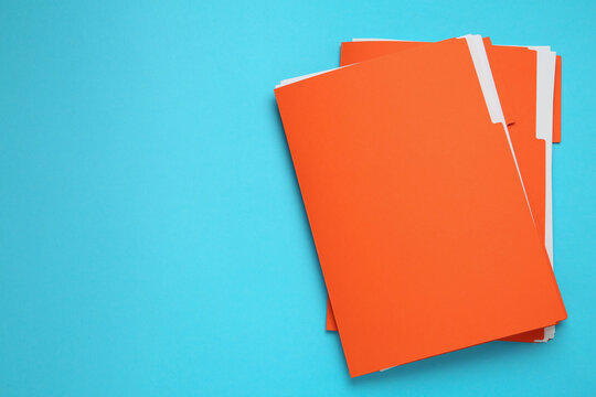 Orange files with documents on turquoise background, top view. Space for text