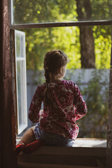 little girl sitting on a window sill