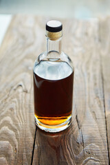 Alcoholic drink cognac or whiskey in a glass bottle on a wooden table.