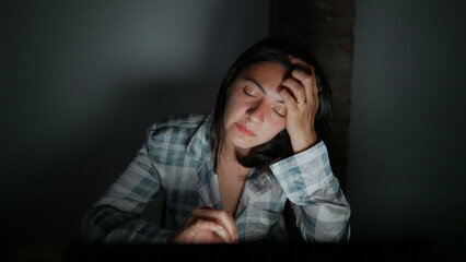 Obraz premium Tired woman in front of computer screen at night alone