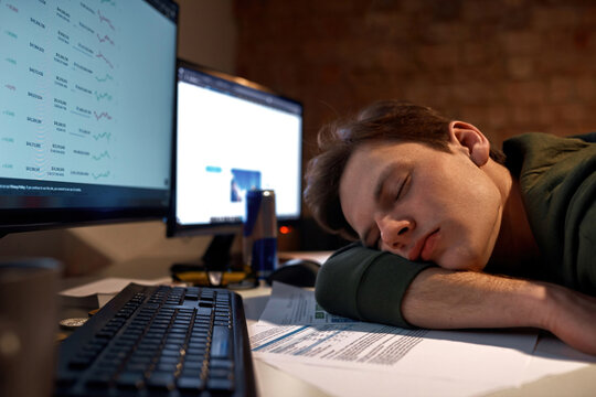 Male trader sleeping on paper documents at table