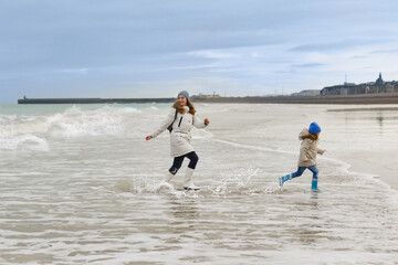 Mother and daughter run away from the waves